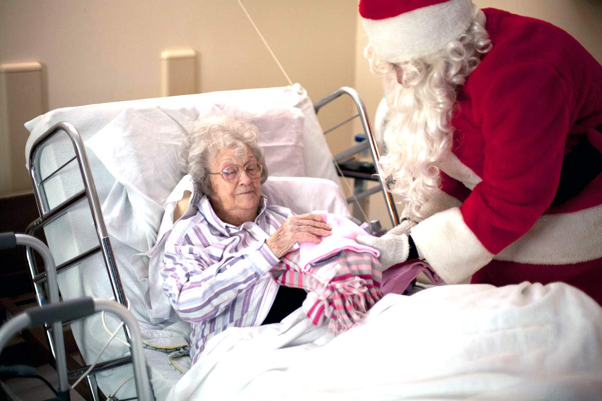 santa delivers gifts of warm blankets to senior woman in bed 2