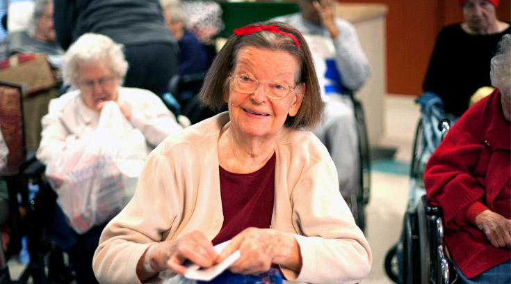 group of senior women in assisted living facility open donated holiday gifts