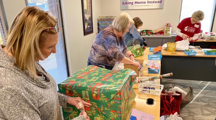 group of volunteers wrapping holiday gifts for seniors